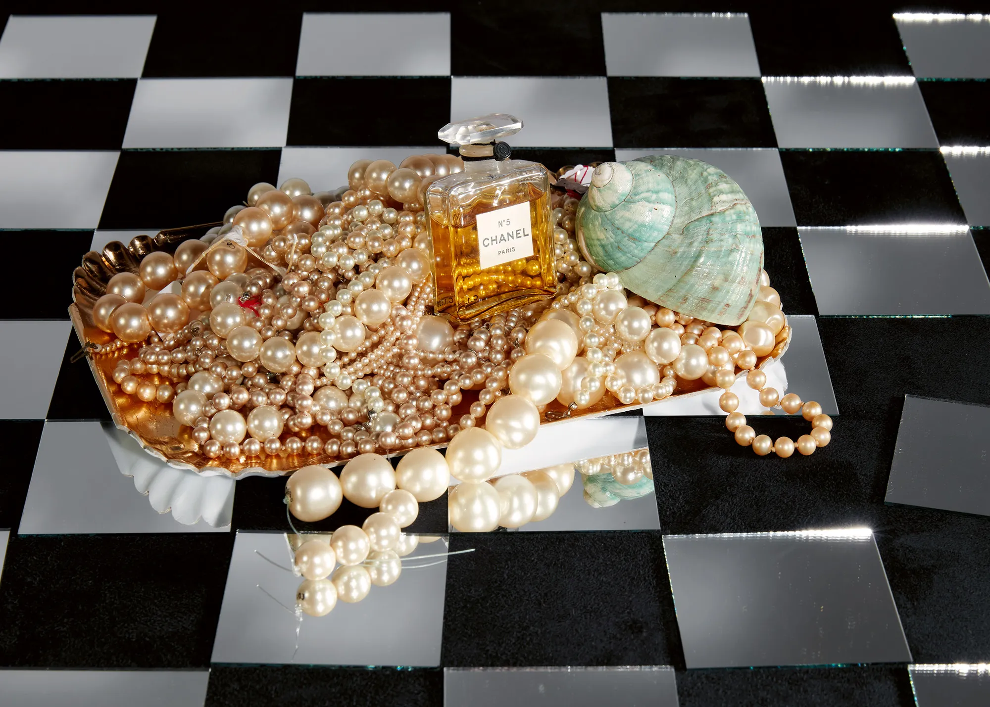 A display of loose jewelry lays gathered on a black and white tiled floor.