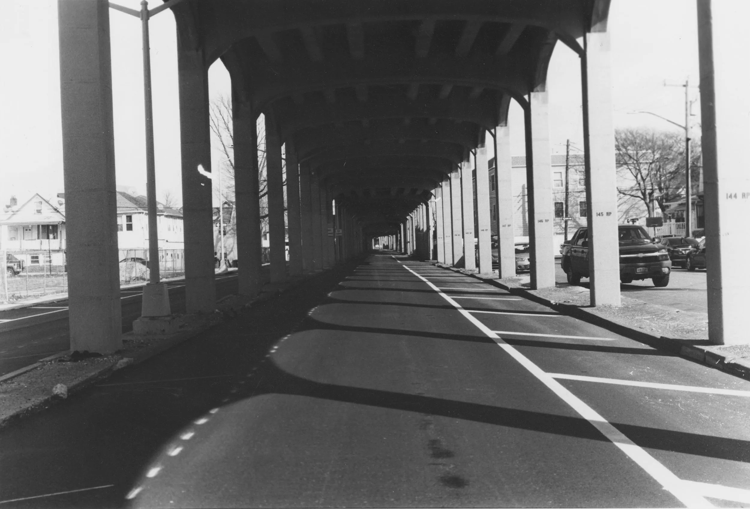 A city street that runs beneath above ground train tracks. 
