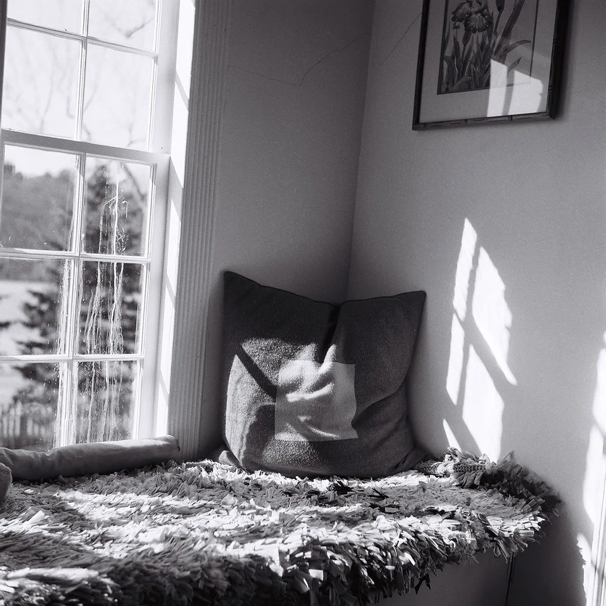 The corner of room where a beam of light is cascading over a pillow. 