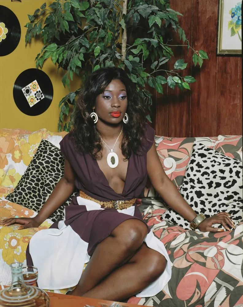 A woman dressed up in makeup and an elegant dress on her couch. 