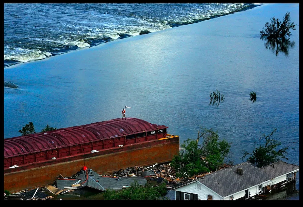 Someone waving a white flag on the top of a flooded building. 