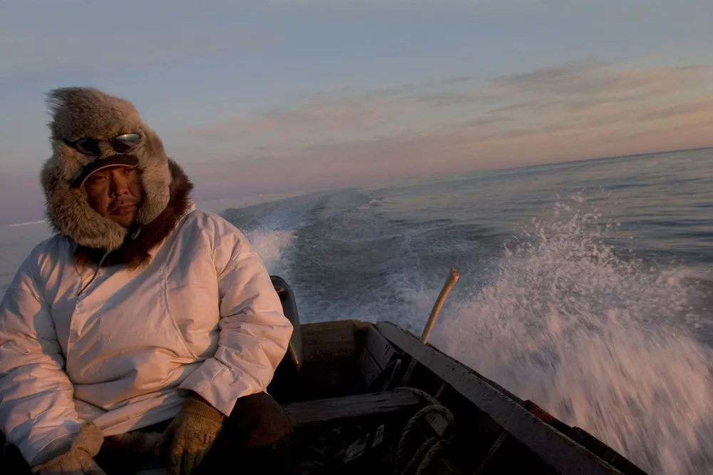 A northern native American sitting on the back of a motorboat. 