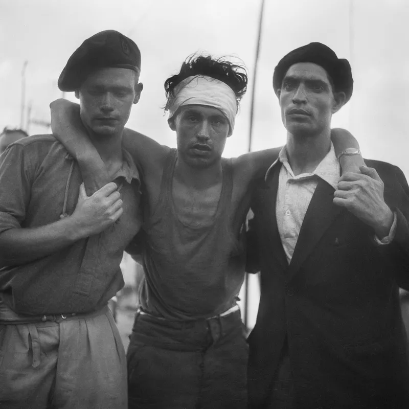 A man with a bandaged forehead being held up by two others. 