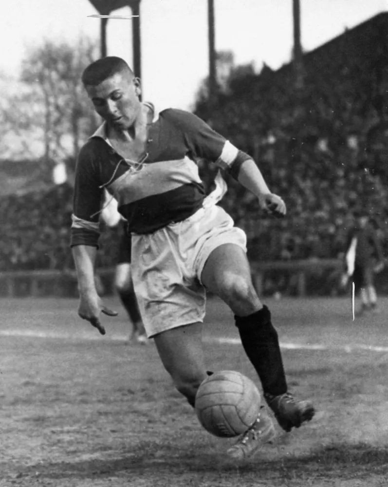 An dirty soccer player playing on a muddy field. 