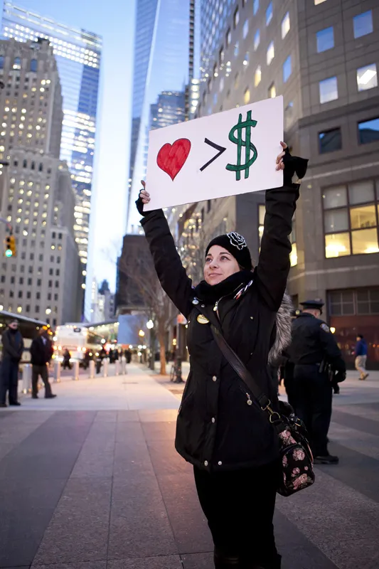 A woman with a sign that says "Love is greater than money."