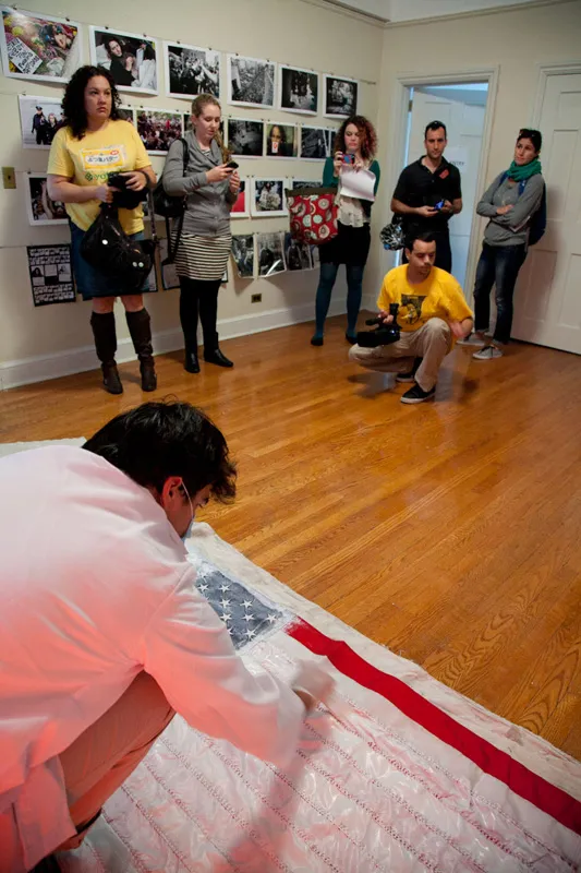 Someone painting the red stripes of the American flag while people watch him. 