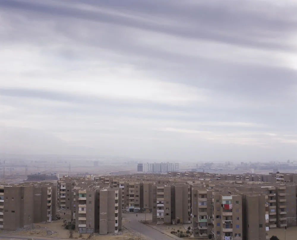 A hazy cityscape of identical apartment buildings. 