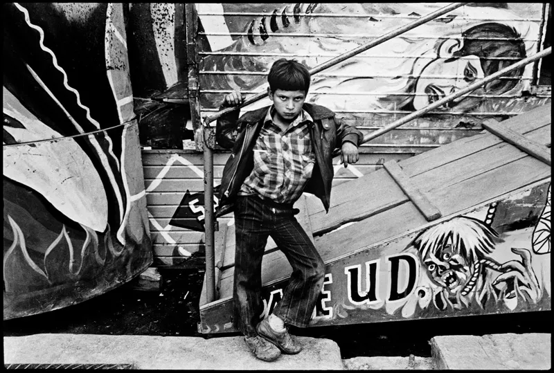 A young boy leaning against a haunted house, trying to look intimidating. 