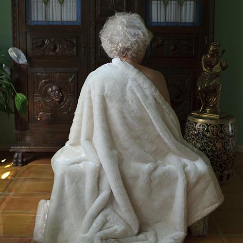 An elderly lady wrapped in a blanket.