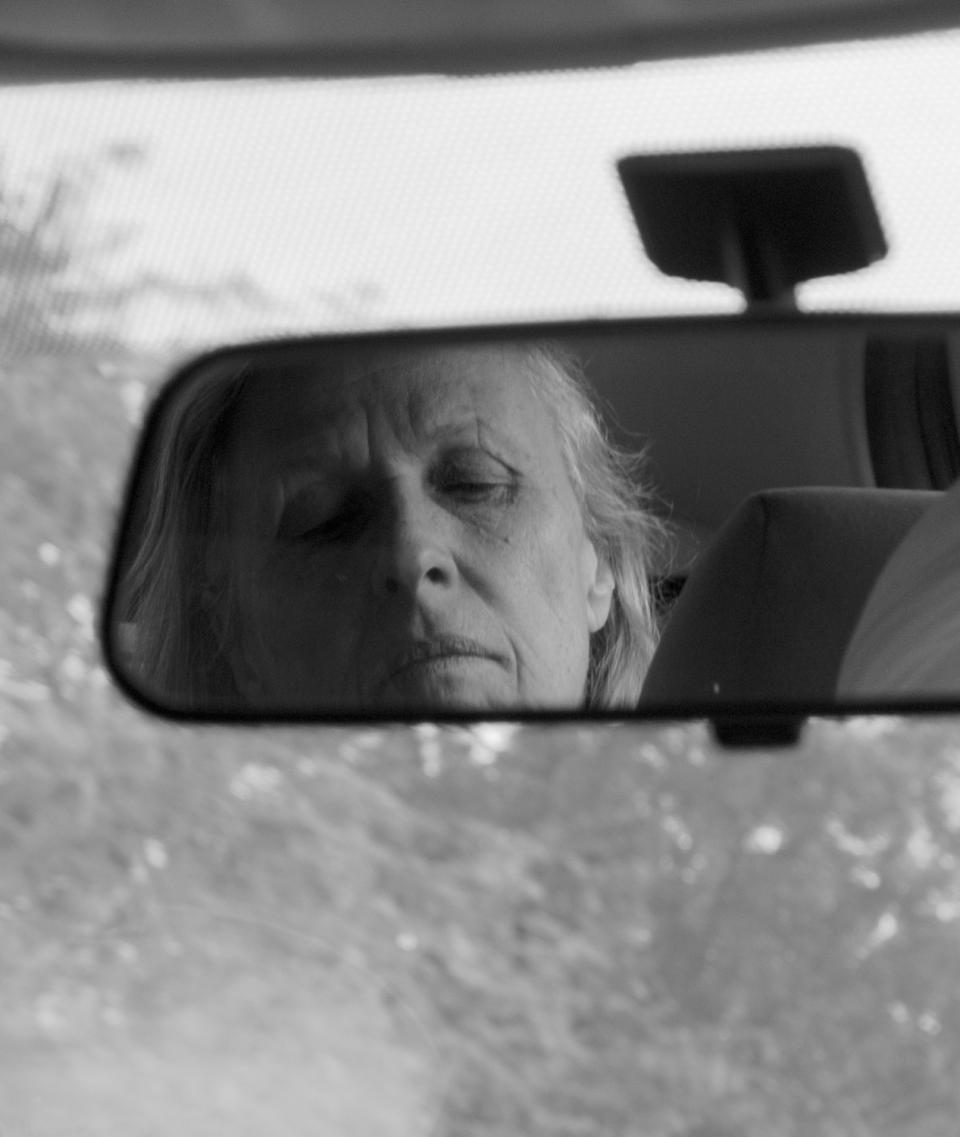 A photo of the rear view mirror with a woman in it.