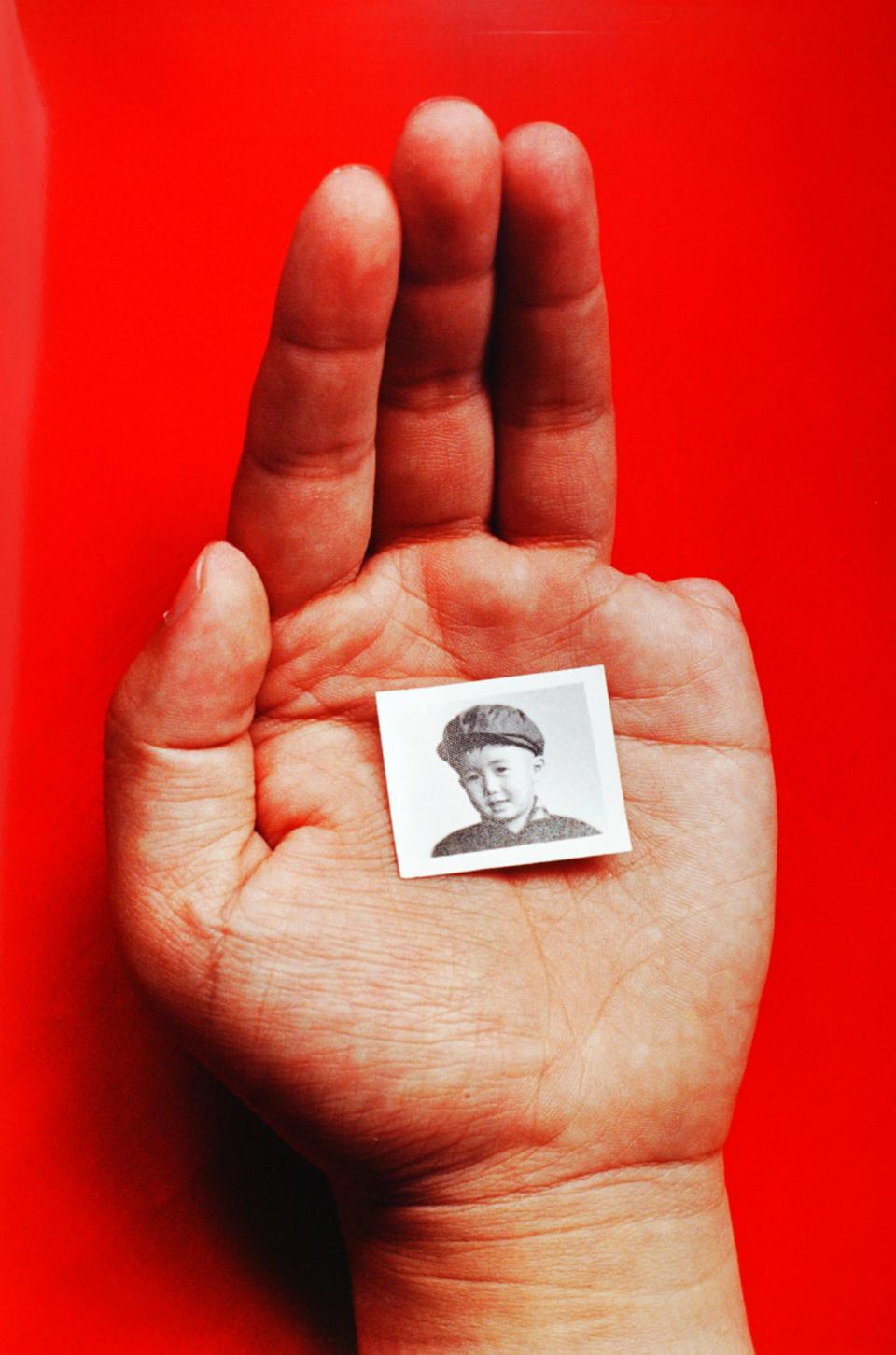 A hand holding a photo of a small boy.