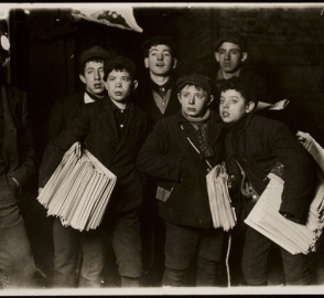 Newspaper boys looking at something off screen. 