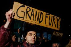 A man holding a sign saying grand fury.
