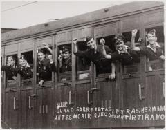 Young men in WWII waving their hands as they depart on a train. 