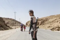 A person walking in the middle of the road with a gun.