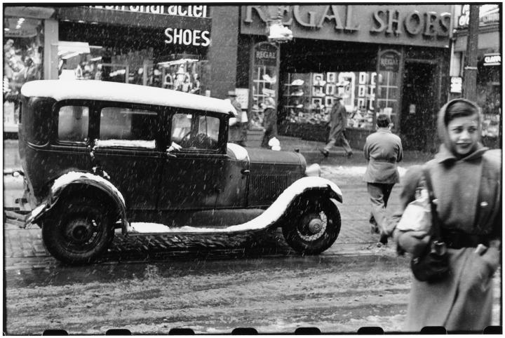 An antique photograph with a car and person.