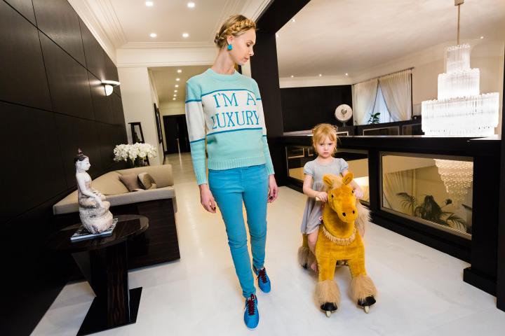 A lady and a child walking side by side in an apartment.