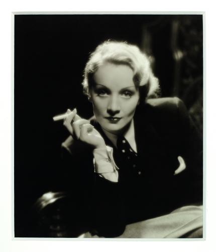 Dietrich looking into the camera and brandishing a cigarette. 