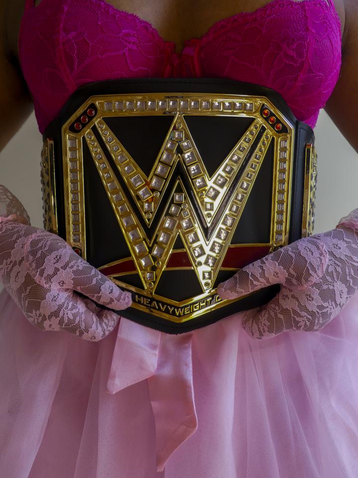 A young woman in her underwear wearing the WWE Belt. 
