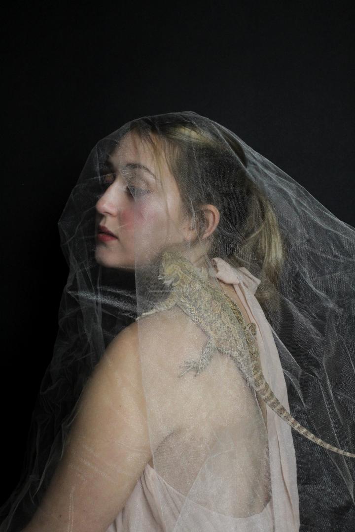 A woman with a lizard on her shoulder.