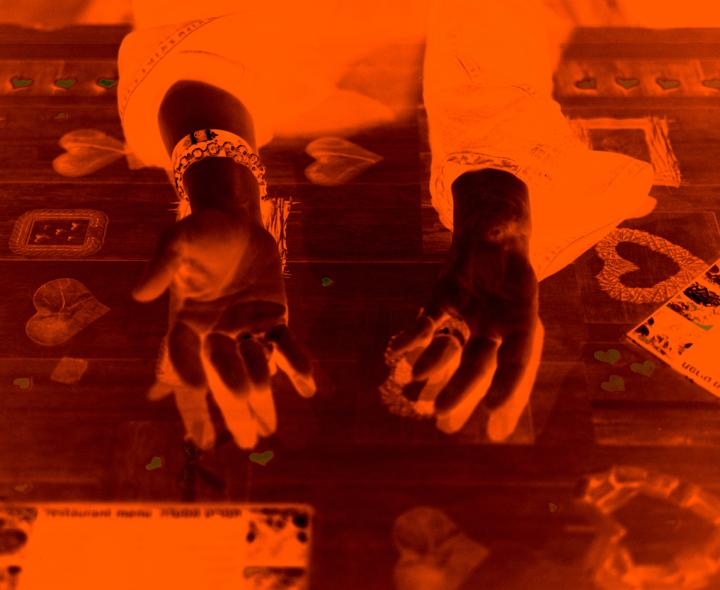 A negative shot of two hands raised up. 