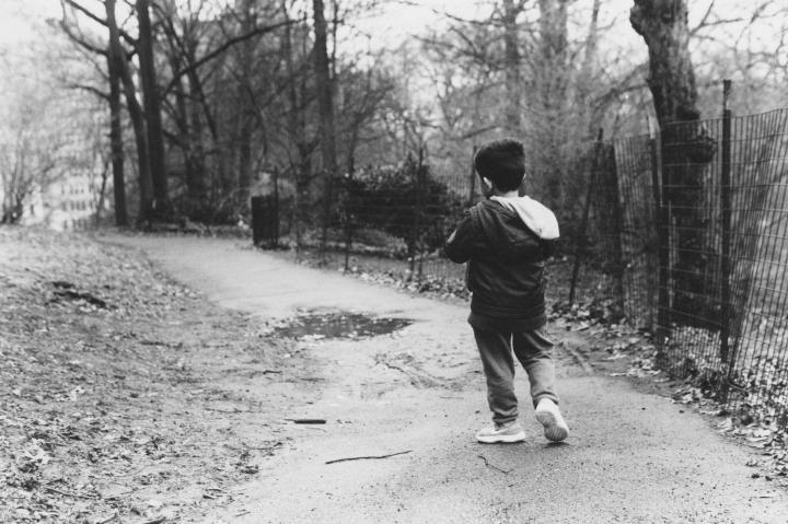 A young boy walking through a park. 