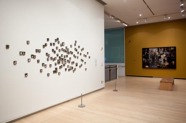A photography exhibition featuring a wall of tiny photographs scattered across its surface. 