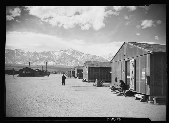 Rows of makeshift houses on the plains, with great snow peaked mountains in the background. 