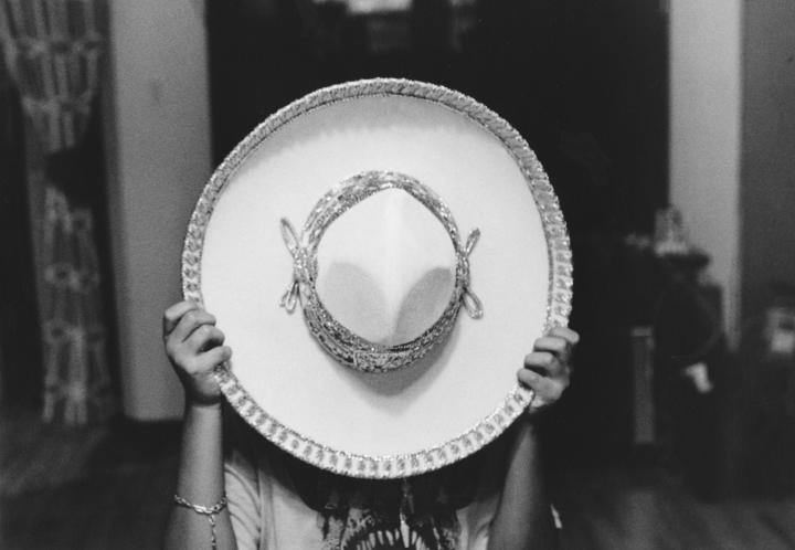 A women covering her face with an ornate white sombrero. 
