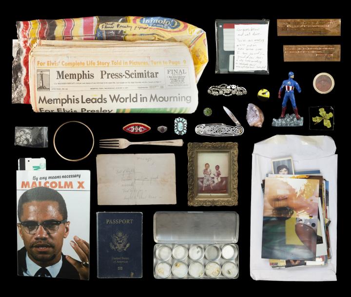 A collection of somebody's possessions including a US passport, Captain America action figure, and picture of Malcolm X.  