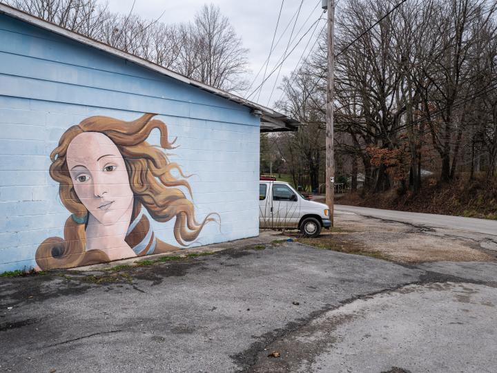 The side of a garage with a mural of the Birth of Venus. 