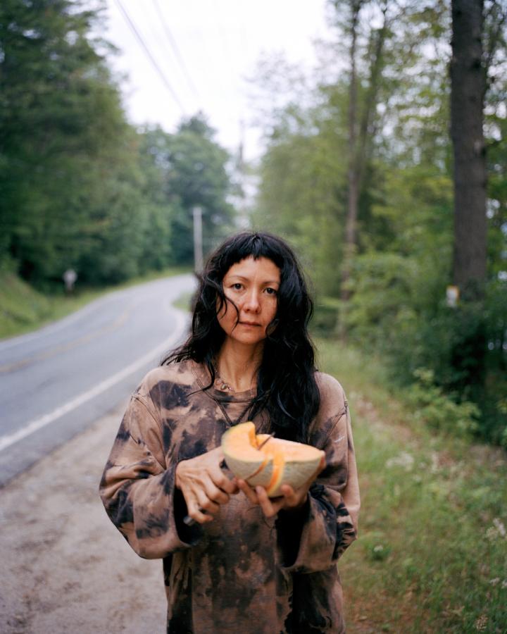 Lady cutting melon on an open road