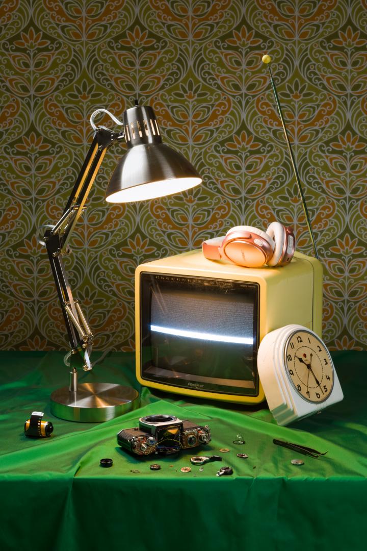 A lamp, tv, camera parts and a clock