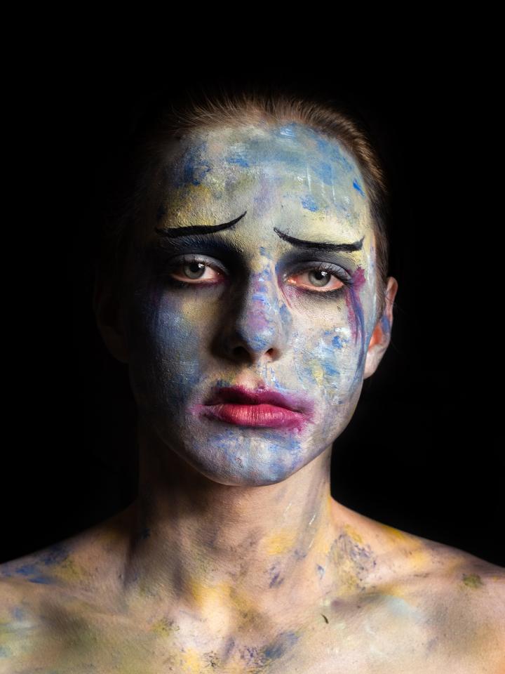 A photo of a sad lady with paint all over her face