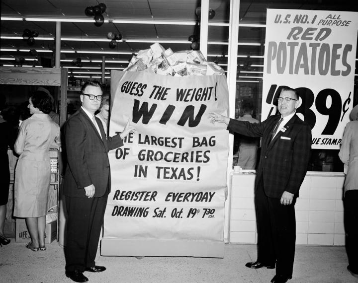 Two men next to a ‘guess the weight’ contest. 