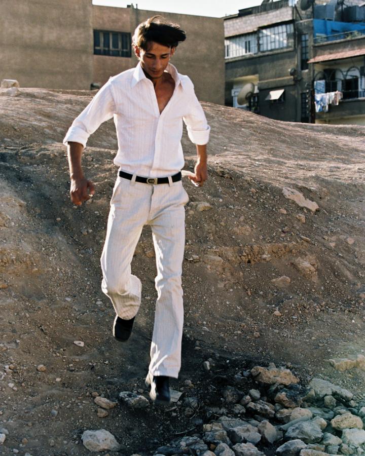 A man walking down a in a white outfit.