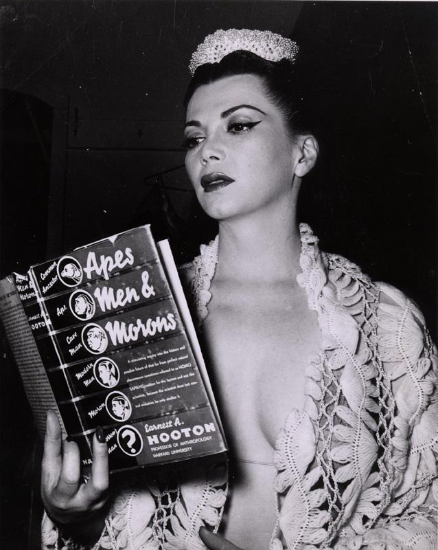 A woman reading a book titled, "Apes, Men, and Morons." 