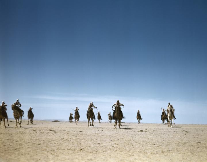 A group of men in the desert riding horses. 