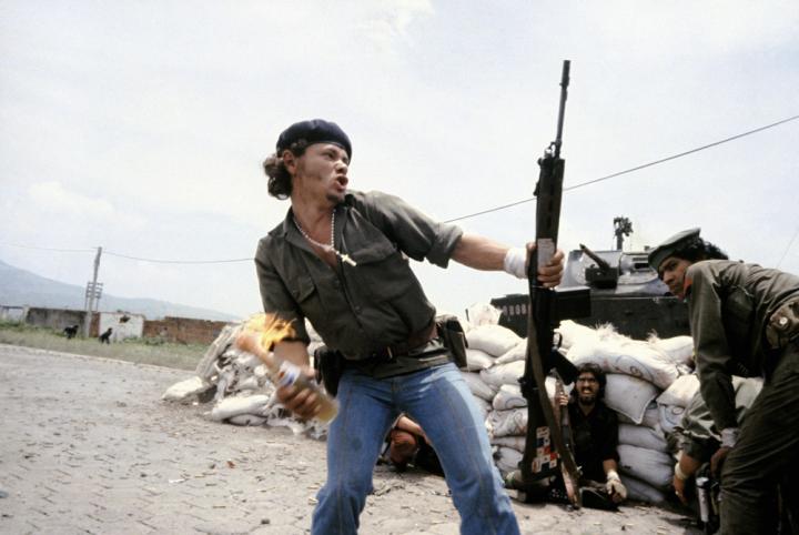 A man holding a gun and a molotov.