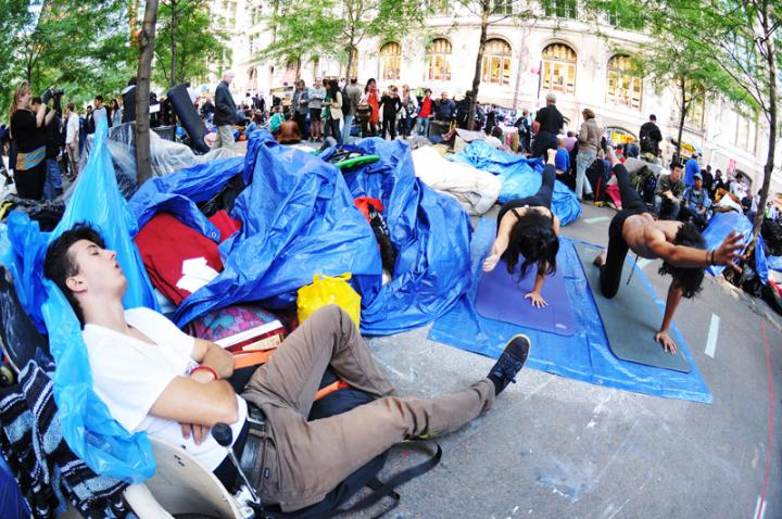 Someone sleeping next to a couple doing yoga during the Occupy movement. 