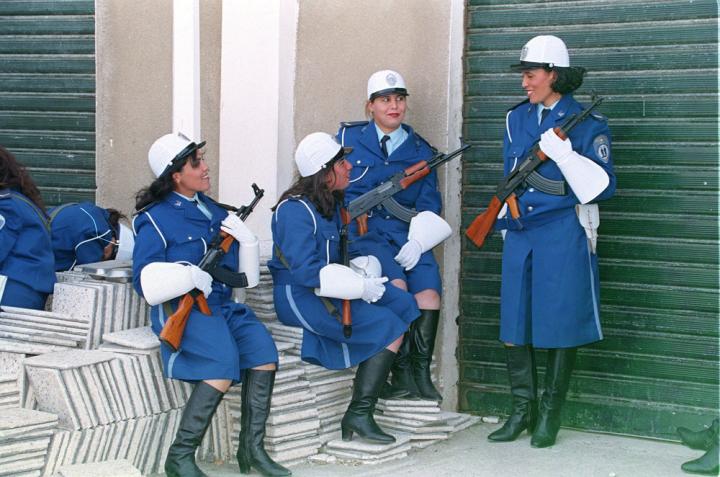 Four young women in blue uniforms armed with AK-47s.