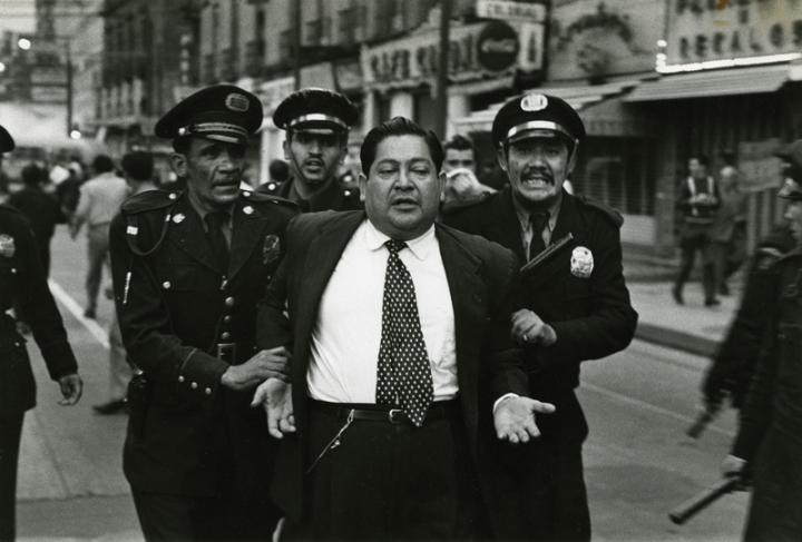 A man in a suit arrested by three cops. 