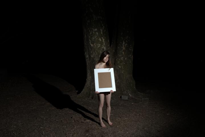 Woman holding empty picture frame in the woods