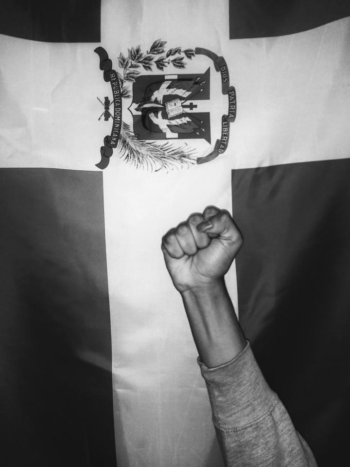 A fist raised in front of the Dominican flag. 