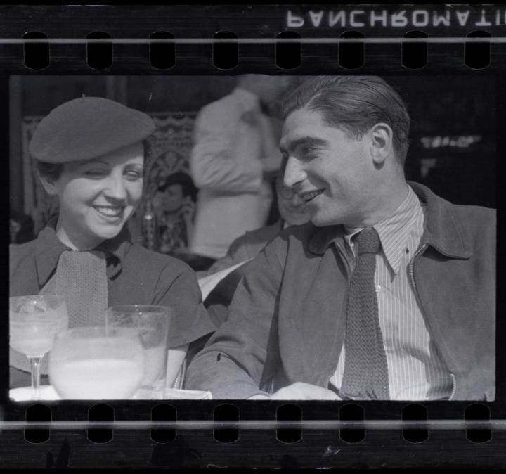 A well dressed man and woman laughing on the terrace of a restaurant. 