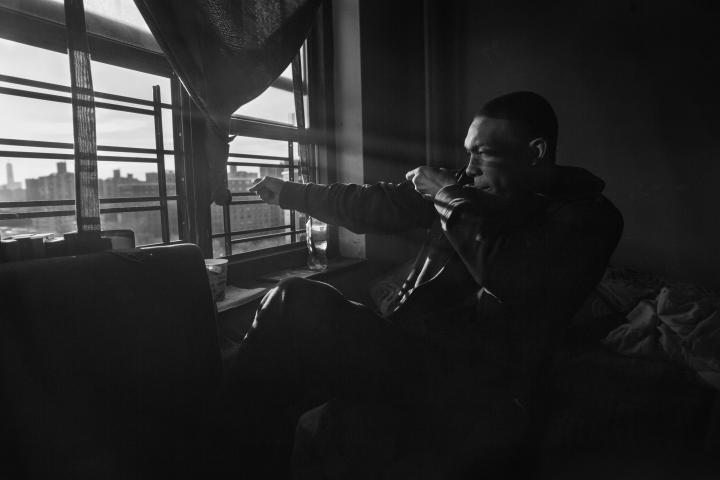 Black and white image of a man looking out a window
