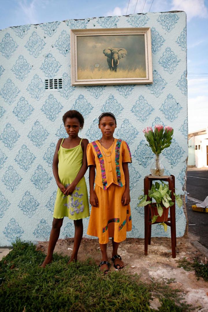 Two girls standing outside in front of a painted wall