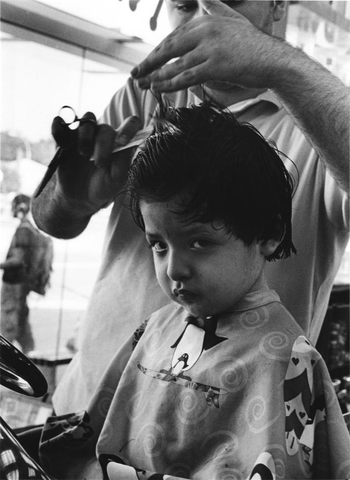 Black and white image of a kid getting a haircut