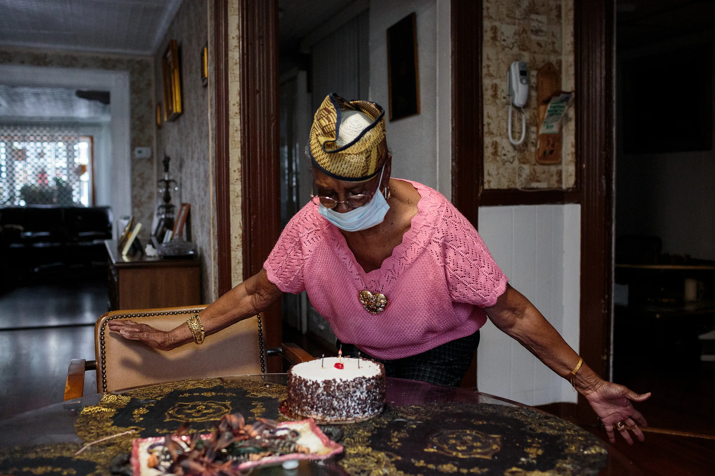 An elderly lady blowing out the candles.