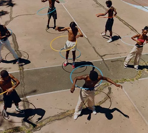 Kids outside playing with a hula hoop.